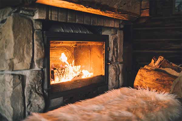 Forked River chimney service, Fire in fireplace with fluffy white rug in front and large log on side